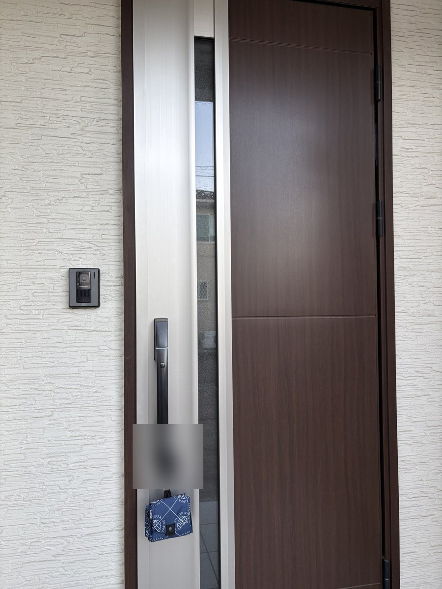 玄関ドアの取っ手にたたんだ状態で吊るした置き配バッグOKIPPA